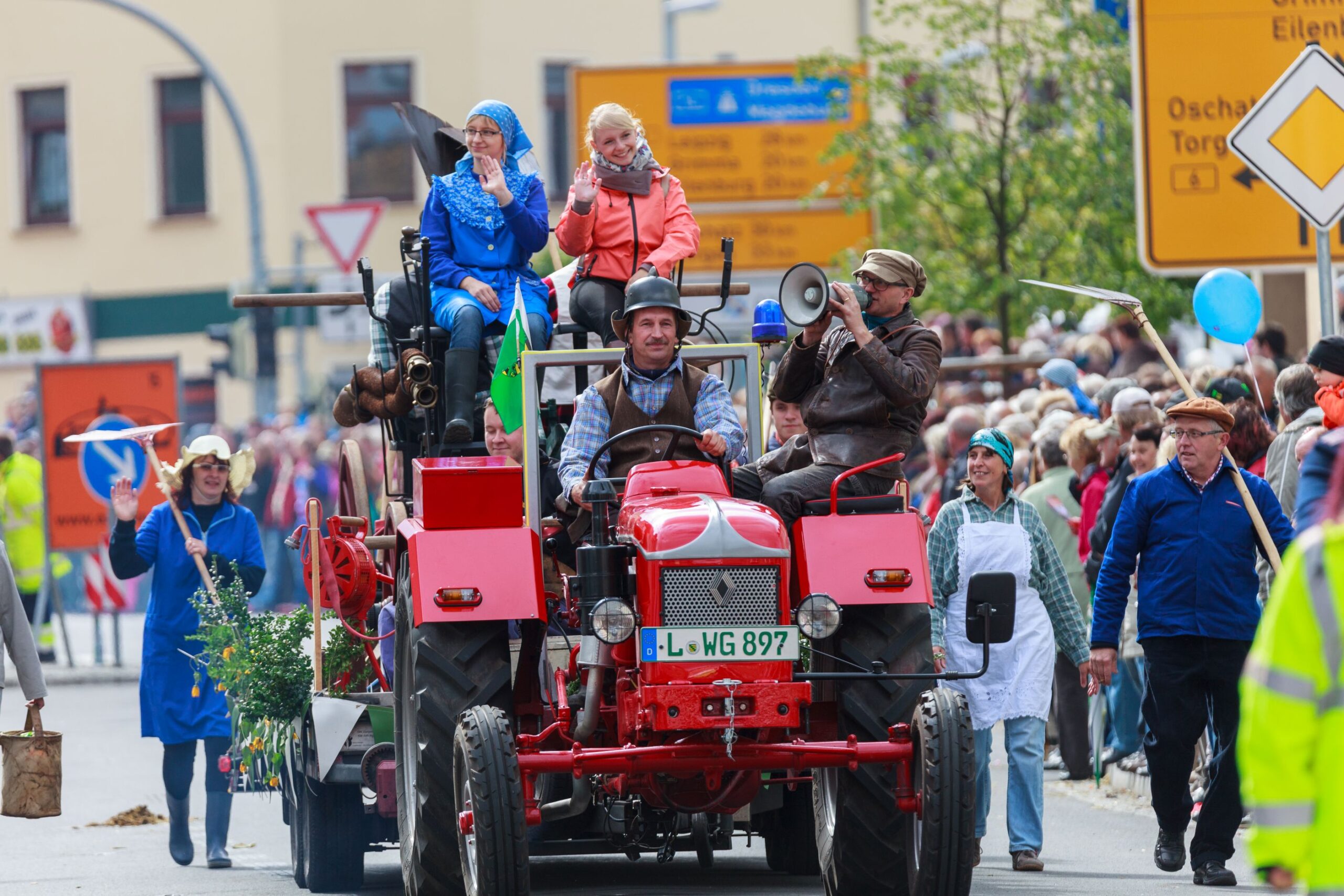 Menschen fahren auf einem roten Traktor bei einem Festumzug mit.